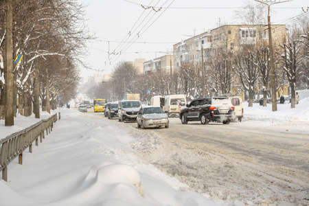 Lutsk, Ukraine - February 12,2020: Stuck car in snow and ice. City street after blizzard. Buried vehicle in snowdrift. Parking in winter after snowfall. Uncleaned road. Record-breaking amounts of snowのeditorial素材