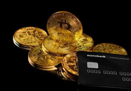 Lutsk, Ukraine - May 1, 2021: Golden coin with bitcoin logo and credit card by monobank. Crypto currency BTC and bitcoin rewards card by Universal bank. Digital electronic money or e-cash paymentのeditorial素材