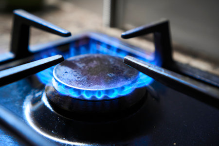 Cooker as heater. Wastage of natural resources. Blue flame from gas hob produce greenhouse gas emissions. Kitchen stove grate on a burner fuelled by combustible natural gas or syngas, propane, butane.の写真素材