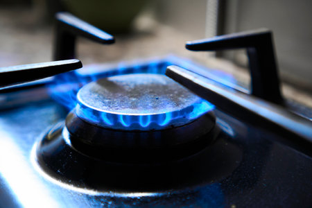 Cooker as heater. Blue flame from gas hob produce greenhouse gas emissions. Wastage of natural resources. Kitchen stove grate on a burner fuelled by combustible natural gas or syngas, propane, butane.の写真素材