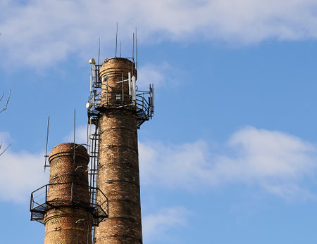 Two cell tower above cellular base station. Brick chimneys of boiler building and set of transmitter, receiver, transceivers. Industrial towers or pipe with mobile antennas. Smokestacks with cell siteの写真素材