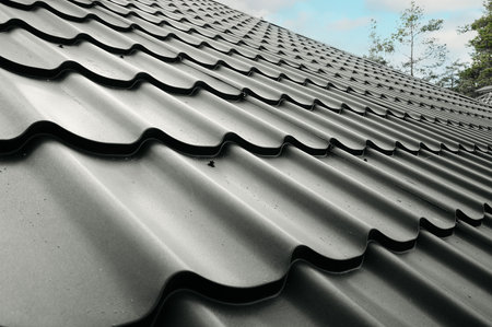 Close-up house roof with steel roofing sheet. Traditional metal shingle tiles. Gray modular tile...