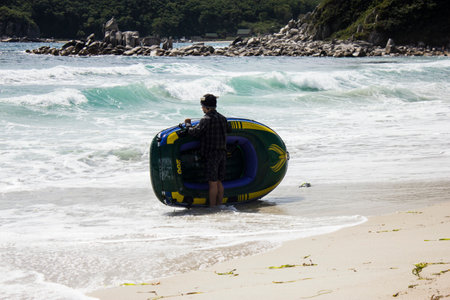 Sea of Japan, Japan, June 21 2023 - Active Vacation Fun: Men with boat on a Sunny Beach