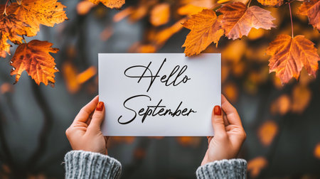 Hello september. Hello september text on white paper in female hands on autumn background.の素材