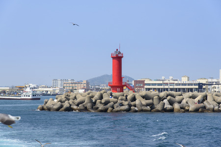 red Lighthouse on a seawall in the Moseulpo in Jeju Island, Korea.のeditorial素材