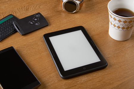 E-book device with Smart key, card wallet, smart watch, smart phone and a cup of coffee on a wooden table. The device is a dedicated device for reading e-books.の写真素材