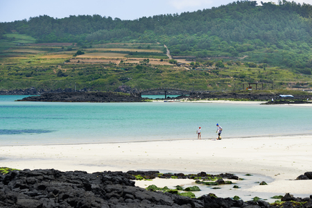 Jeju, Korea - May 22, 2017 : Hamdeok beach and Seoubong peak in Jeju, Korea. Hamdeok is famous beach for its clean blue water and white sand. And Seoubong peak is a part of Olle trail course No.19.のeditorial素材