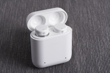 wireless cordless earbuds with chargeable case on a fabric background