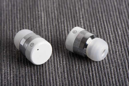 close-up of wireless cordless stereo earbuds on a fabric background