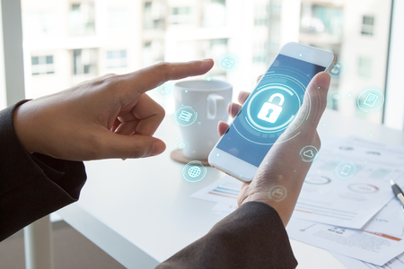 Business, technology, internet and networking concept. businessman working on his laptop and mobile in the office select the icon security on the virtual display. Cyber securityの写真素材