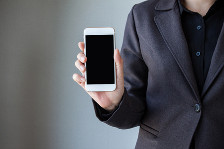 Business woman hand holding mobile phone. Business woman working on a digital tablet. Business woman show cell telephone in black dressed suit on white background, Close up hand man use mobile phoneの写真素材