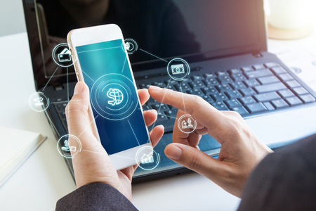 Online banking payment communication network digital technology application development mobile smartphone sync app: Close up hand business woman/ man holding mobile phone with Mobile banking icon flowの写真素材