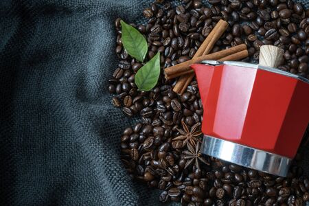 Coffee beans with leaf on vintage black fabric background. Top view moka pot coffee maker with copy space. Flat lay.の写真素材