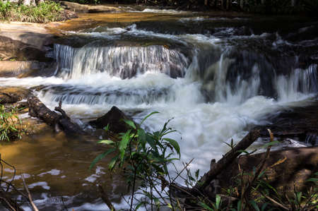 Kbal Spean Waterfall in rainy season flowing on carved stones which lie under the waterの写真素材