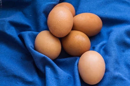 A pile of fresh eggs placed on blue cloth
