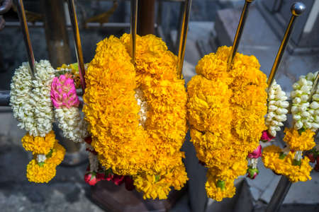 Traditional Thai flower garlands made of jasmine,rose petals and marigolds in front of the Buddhist altar.の写真素材