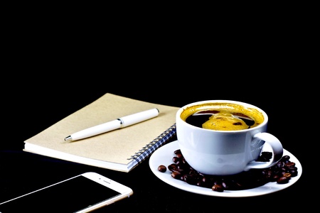 Close up view of a cup of coffee with coffee beans on dark backgroundの素材