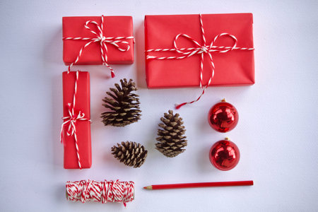 Christmas gift box with red ribbon and pine cone on white background.の写真素材