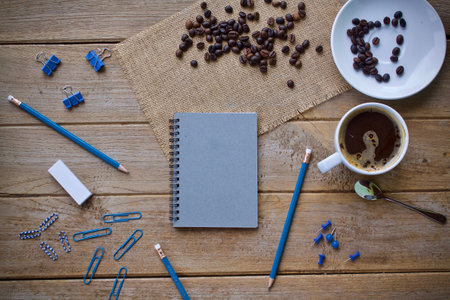 Coffee cup and notepad with pencils on wooden tableの写真素材