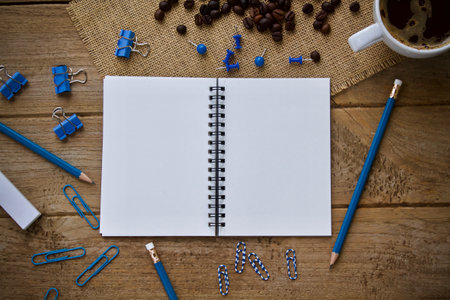 Blank notepad with coffee cup and pencils on wooden table