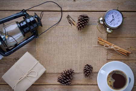 Coffee cup, vintage lantern, gift box and pine cones on wooden backgroundの写真素材