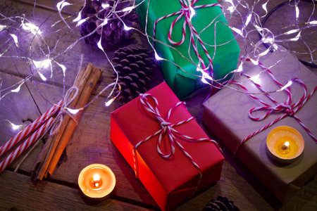 Christmas presents and lights on rustic wooden background with copy space.