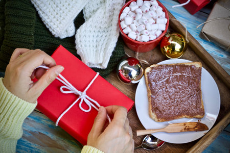 Hands of a woman decorating a Christmas cake on a wooden tray