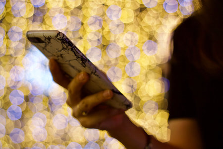 Woman using mobile smart phone with bokeh lights on background.の写真素材