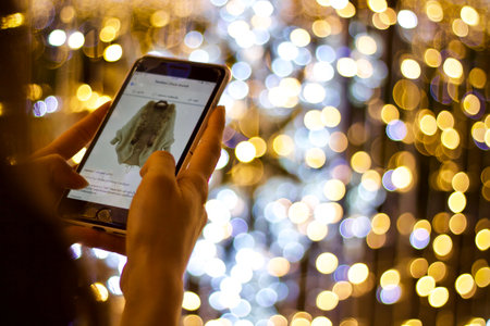 Woman using mobile smart phone with bokeh lights on background.