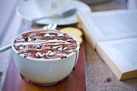 Cup of hot chocolate and book on wooden table, stock photoの写真素材