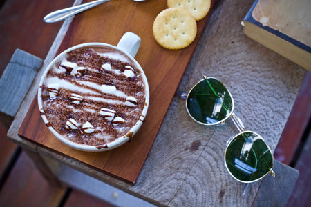 Cup of hot chocolate with marshmallow and sun glasses on wooden tableの写真素材