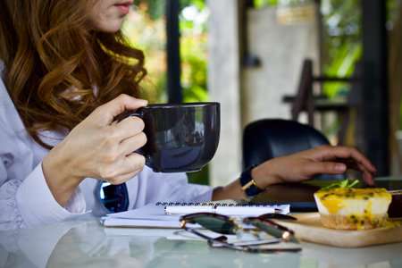 Woman drinking coffee in a coffee shop. Close-up of a female hand holding a cup of coffee.の写真素材
