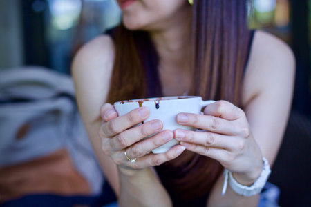 Woman drinking coffee in coffee shop. Close up of female hands holding coffee cup.の写真素材