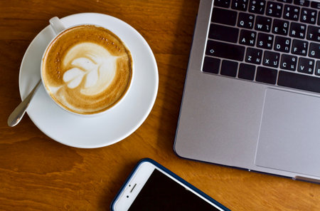 Coffee cup and laptop on the wooden table, stock photoの写真素材