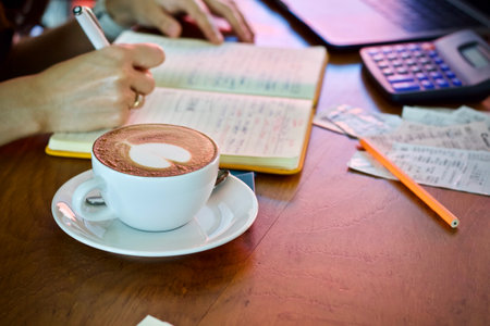Coffee cup and notebook on wooden table in coffee shop.の写真素材