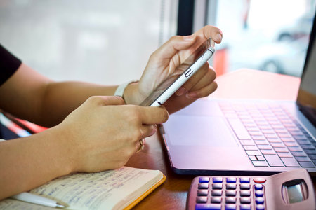 Close-up image of businesswoman using mobile phone and laptop computerの写真素材