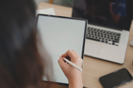 Closeup image of a female designer drawing on digital tablet while working in officeの写真素材