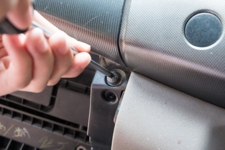 Car mechanic manually screwing or unscrewing a screw by screwdriver - Fixing Vehicle - Do-it-yourself (DIY) concept.の写真素材