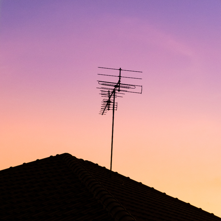antenna on house roof in colorful of sky during sunsetの写真素材
