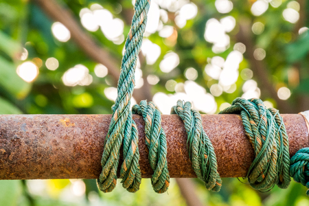 green rope tied on rust metal pipeの写真素材