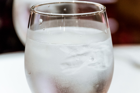 close-up of drinking water and ice with droplet in glass on restaurant table topの写真素材