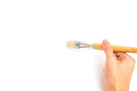 hand holding new wooden paint brush on white paperの写真素材
