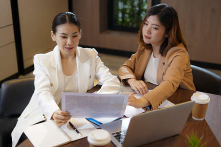 Team work process. Two women with laptop in open space office. Business concept., two women is meeting for business matching. ,Two young beautiful asian business woman in the conversation.の写真素材