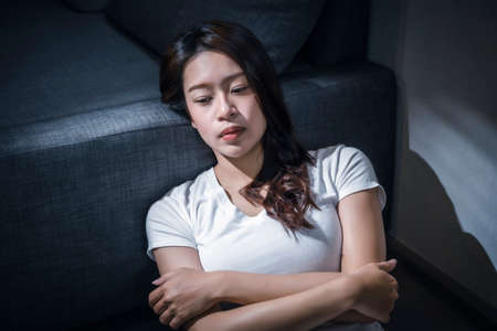 Portrait of young asian woman sitting on sofa at home.の写真素材