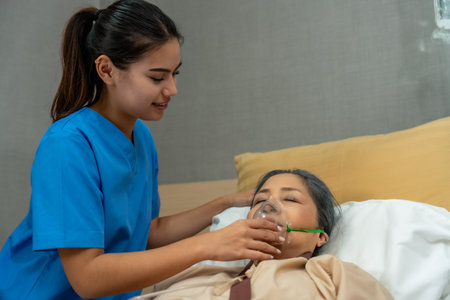Female nurse giving oxygen to a patient in hospital.の写真素材