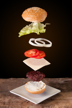 hamburger with flying ingredients placed on wooden planks.の写真素材