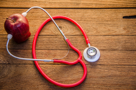 Stethoscope with red apples on wooden background.の写真素材