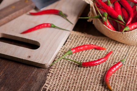 Red hot chili peppers in basket on wooden table.の写真素材
