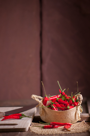 Red hot chili peppers in basket on wooden table.の写真素材