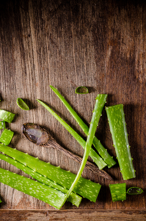 aloe vera gel on wooden spoon with aloe vera on wooden table.の写真素材